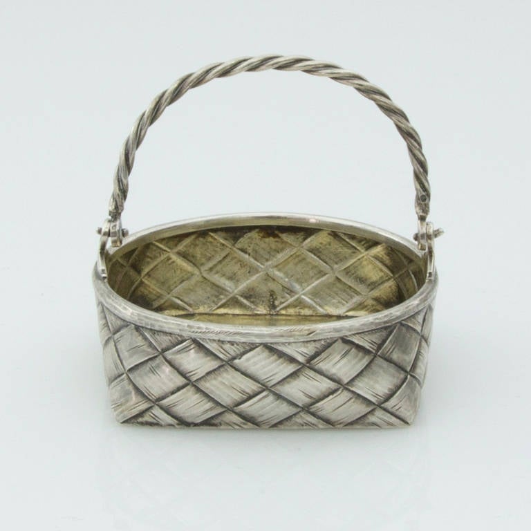 Beautiful antique Russian silver basket, chased to simulate a woven wicker weave picnic basket,  with intertwined silver swing handle and parcel-gilt interior. Measuring 3” in diameter x 3” high; probably fashioned as a bon-bon dish. Handmade with