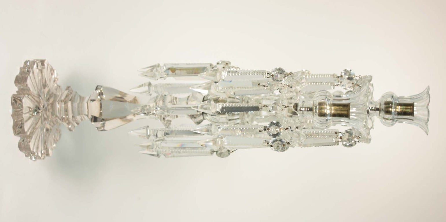 Pair of cut crystal three light candelabra, each tulip shape candle cup fitted with back cut prism attached to its bobeche, and joined with curved arms to the cut standard, over floriform base. Unmarked.
