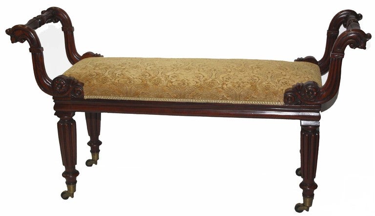 William IV mahogany carved twin handled bench or window seat raised on tapered turned and reeded legs on brass casters; the seat recently recovered.

This stool can serve both as a window seat and as a piano bench, particularly for duets.