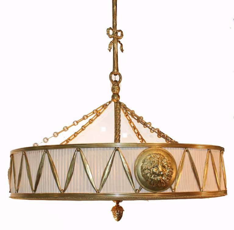 Louis XVI style gilt bronze and pleated silk chandelier with six interior lights; drum form frame suspended by heavy chain from ribbon form shaft, the silk frame modelled as two ribbed bands enjoined by ribbon and accented with lion head medallions;