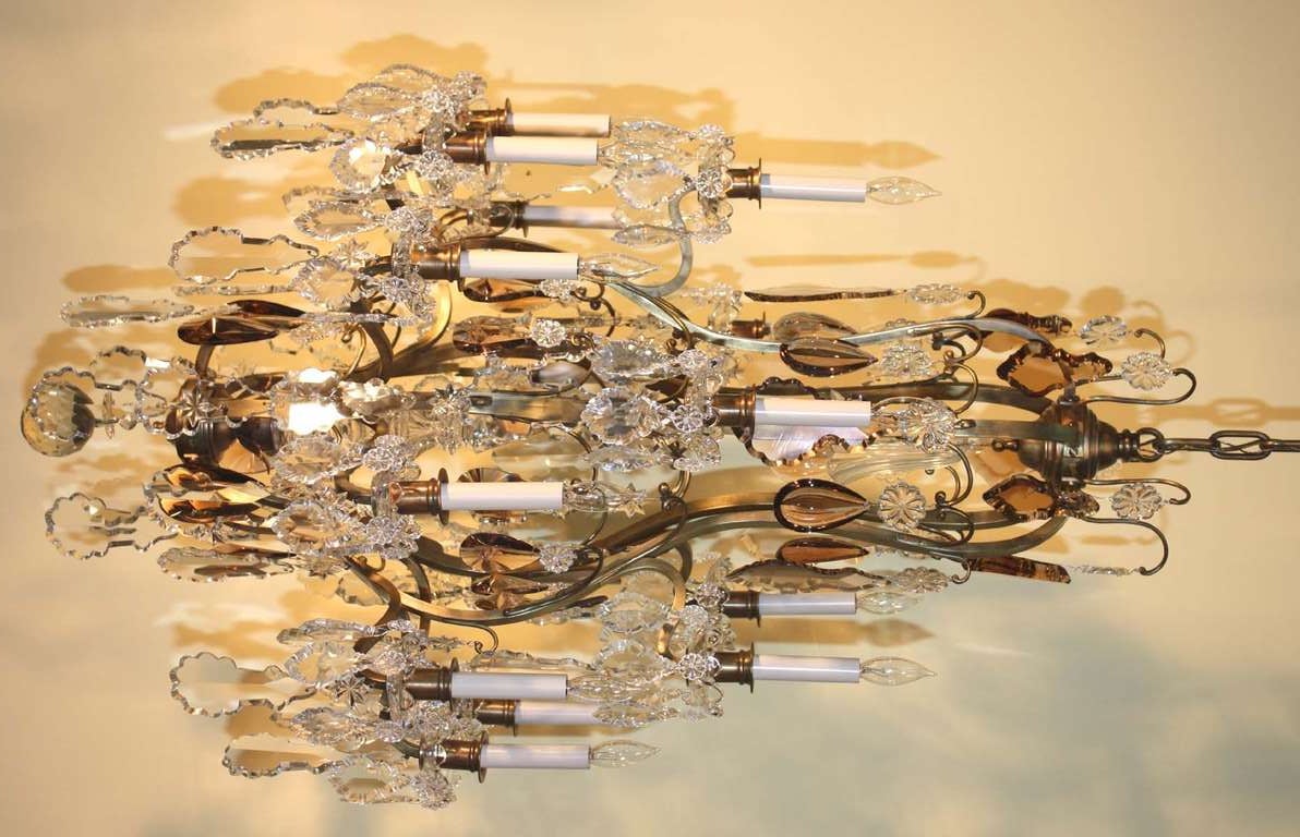 Louis XV style gilt bronze and crystal chandelier with fifteen lights in two tiers, fitted with variegated clear and amber French pendeloques, centered by fluted bellflower from canopy and hollow spire at lower join, terminating in faceted ball. 