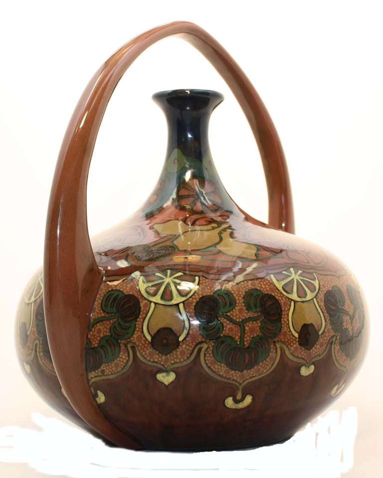 Rozenburg den Haag Art Nouveau bulbous form vase with stylized motifs in high glaze polychrome, fitted with arching basket form handle.