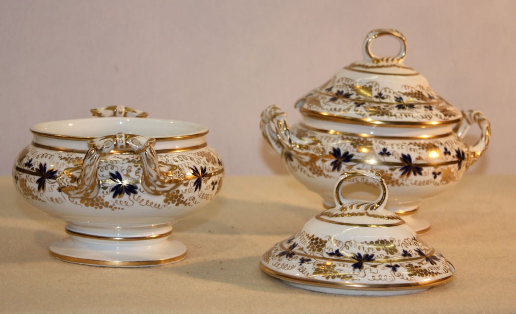 Pair of Derby Porcelain covered sauce tureens and matching shell form dishes, with gilt borders and decorated with gilt fruiting vines, highlighted with blue leaves. Painted red Derby mark. These dessert are not stands but complement well the sauce