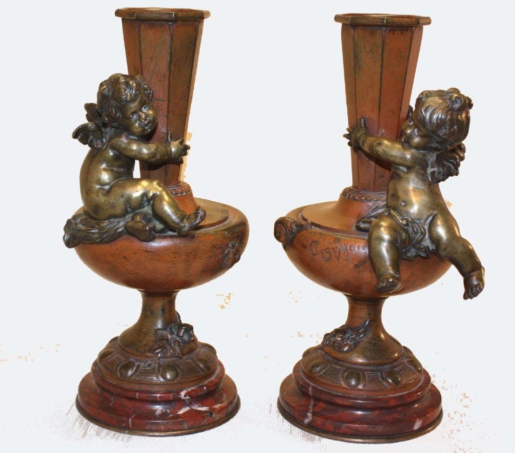 This  pair  is modeled with tapering paneled vases raised on urn-shaped bases . They are a true pair with a cherub facing inwards on each.  Additionally a bee and snail  are cast on each, allegorical of industry and sloth, they are raised on rouge