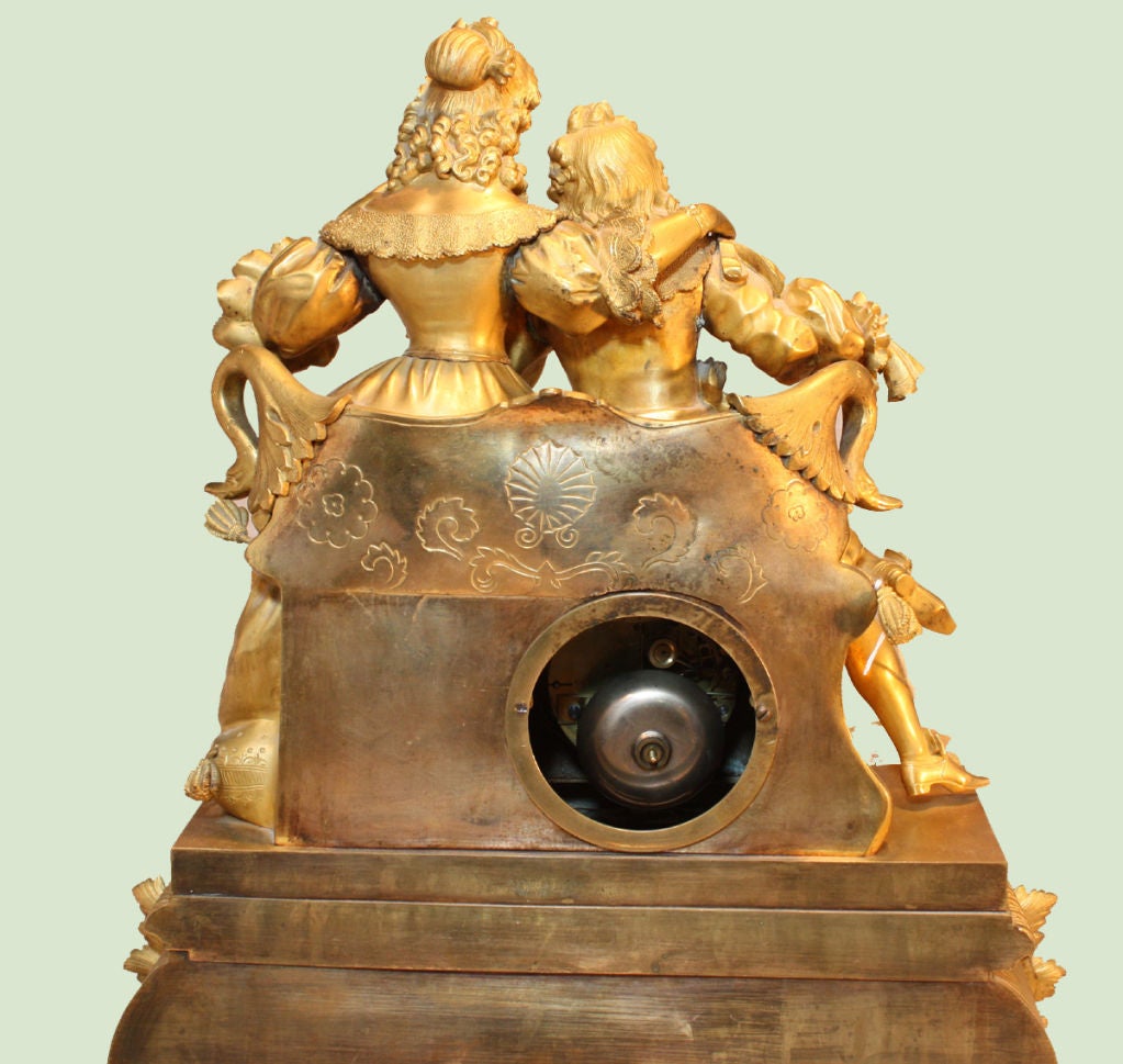 Chiselled and gilt bronze figural mantel clock with courtly Louis XV style clad couple surmounting the dial face with Roman  numerals signed LeJeune Paris over rectangular Rococo style plinth on foliate scroll feet. In working condition, with silk