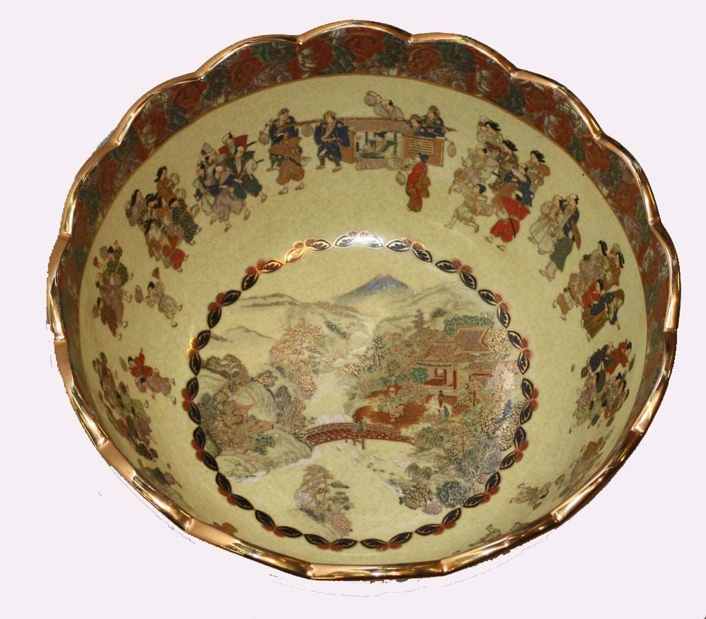 Large Satsuma pottery bowl,  scallpoed border over scenic and figural cartouches surrounded by red floral borders on exterior, the interior centered with a mountainous river scene depicting bridge flanked by houses; bordered by processional figures,