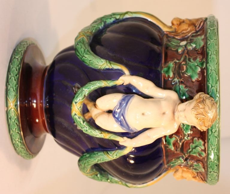 Minton majolica footed jardinière moulded with oak leaf swags joining lion's head masks to applied puttis on cobalt blue ground, under brown leafy neck. Stamped to underside, Minton, 101, and dated 1867.