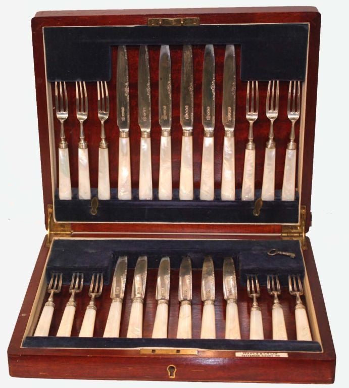 Set of twelve silver dessert/fruit knives and forks with  mother of pearl handles, in original blue velvet lined mahogany box.<br />
Hallmarked Frederick C. Asman, Sheffield, 1922; retailed by Maple & Co. Ltd. Knife=73/8