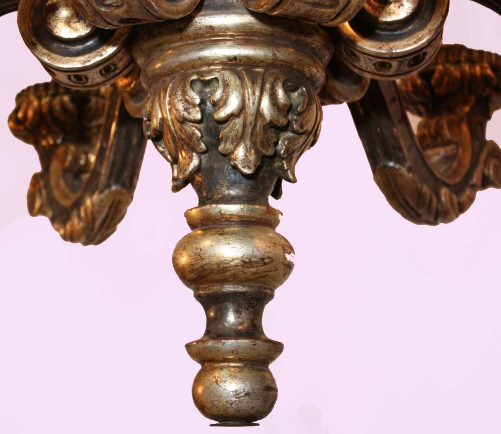Painted and parcel silver gilt six-arm Louis XIV style carved and gessoed wood chandelier.