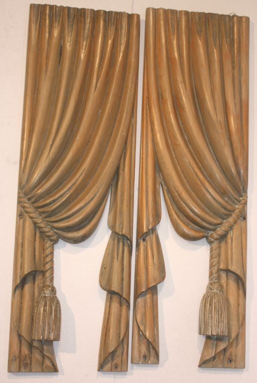 Pair of high relief carved pine drapes with tasseled cord swagging the panels; stripped to pine, with vestiges of original paint.<br />
Originally used as hearse drapes.