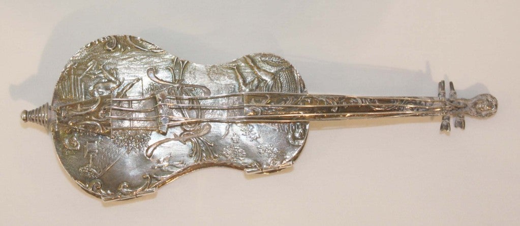Continental, probably Dutch, hinged silver pill box in form of cello, the repoussé body decorated with figures in pastoral landscape. The box opens on two side hinges, to reveal gold washed interior.
Unmarked.