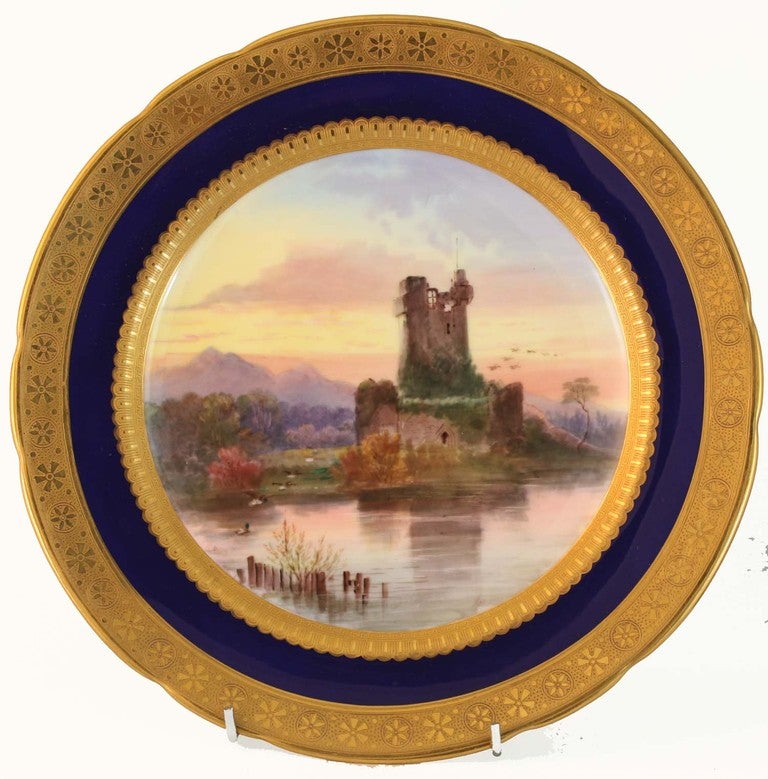 Set of six topographical hand painted scenes within cobalt blue border surrounded by two bands of raised decorated gilding. 
The scenes, portraying  Portsmouth Harbour, Lake Windermere, Tintern Abbey, Fairy Glen, Ross Castle, and Westmorland, are 