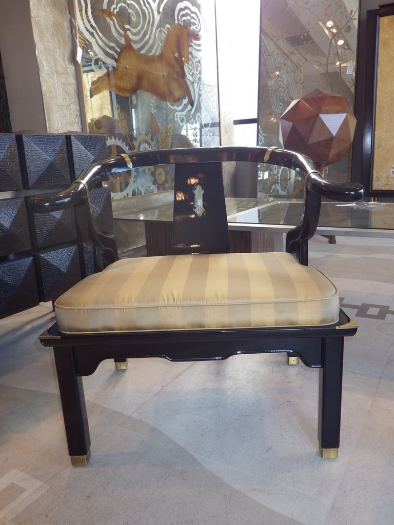 Gorgeous pair of James Mont style armchairs. They feature a black lacquered frame with brass hardware and decorations. Seat cushion is striped satin.