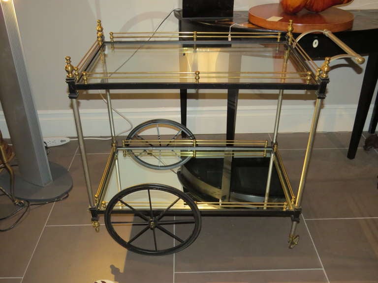 Features two sizes of wheels, brass railings on both tiers. The bottom shelf is made of mirrored glass, the top is clear glass.