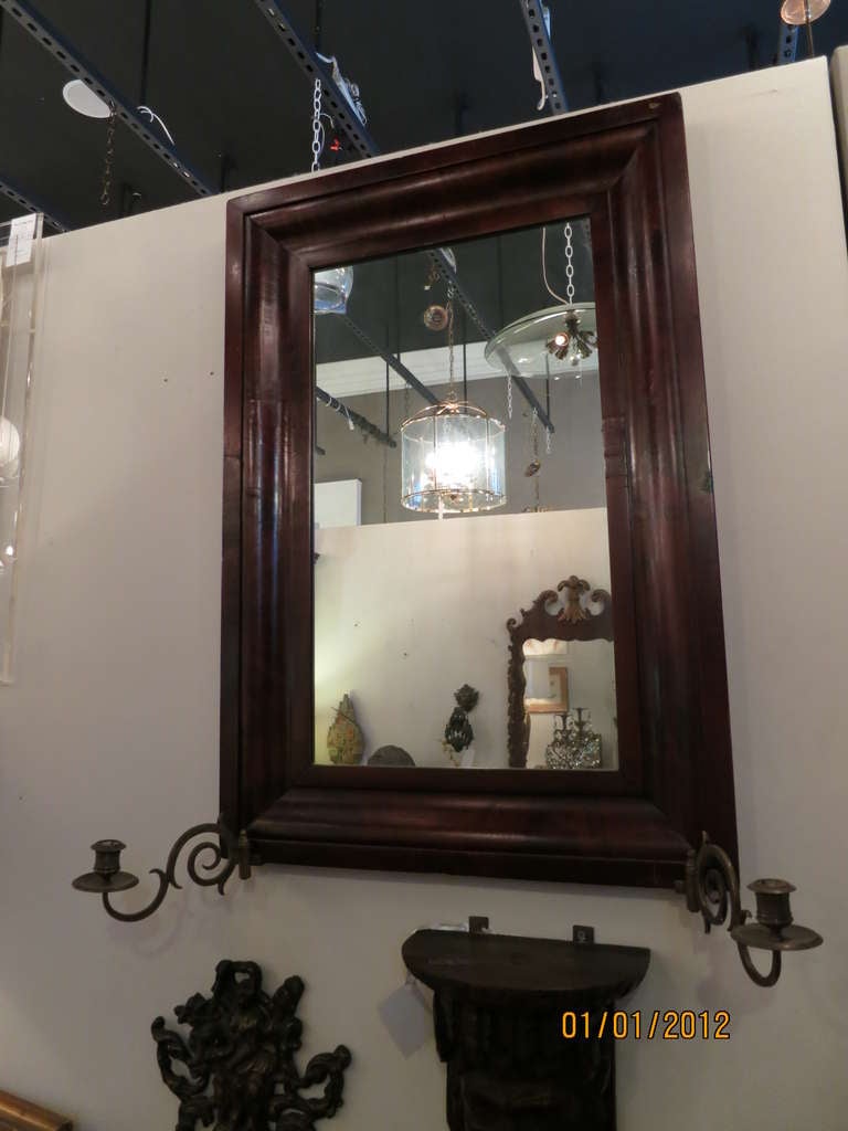This beautiful mirror is made of rosewood and has two attached sconces for candlesticks. Sconces are made of brass and include a hinge for movement.