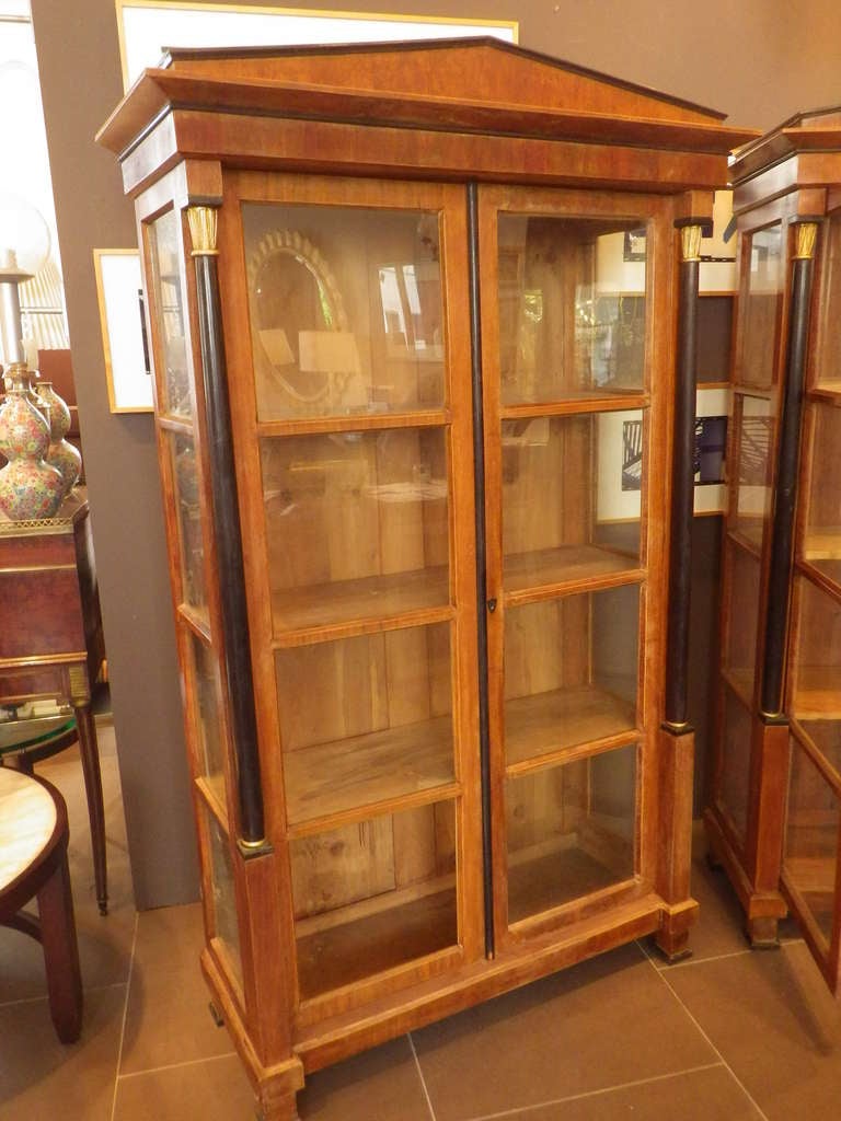 Elegant pair of Biedermeier armoires with original finish. Front and sides have glass. Inside features three shelves.