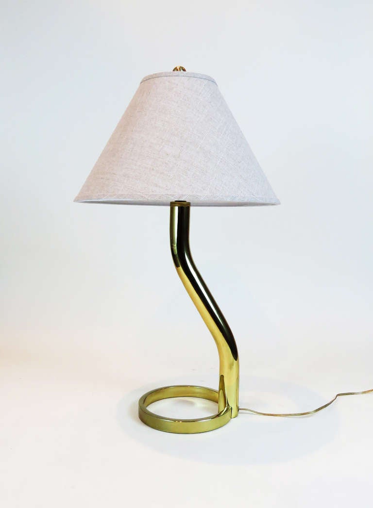 Unique brass table lamp with round base welded onto a body with slight angles going upward. The finial is weighty and large. Beautiful shiny brass.