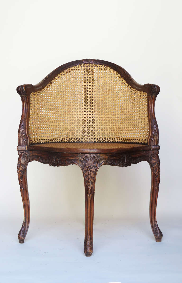 18th c. French corner chair with caned seat and back. The hand-carved frame has been kept perfectly intact.

The back of the chair is caned on both sides of the wood.