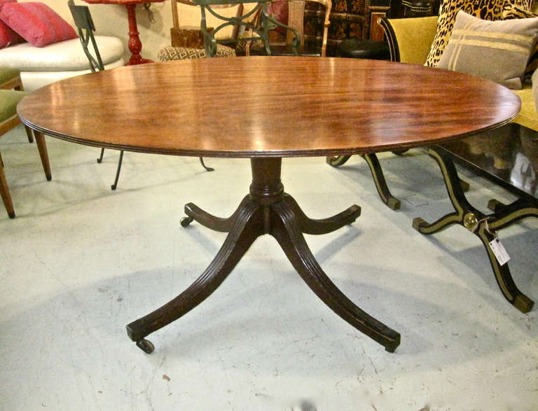 This is a good English Regency oval Breakfast Table that dates to c. 1810-1820. The table features a reeded single board solid figured mahogany top that measures 48