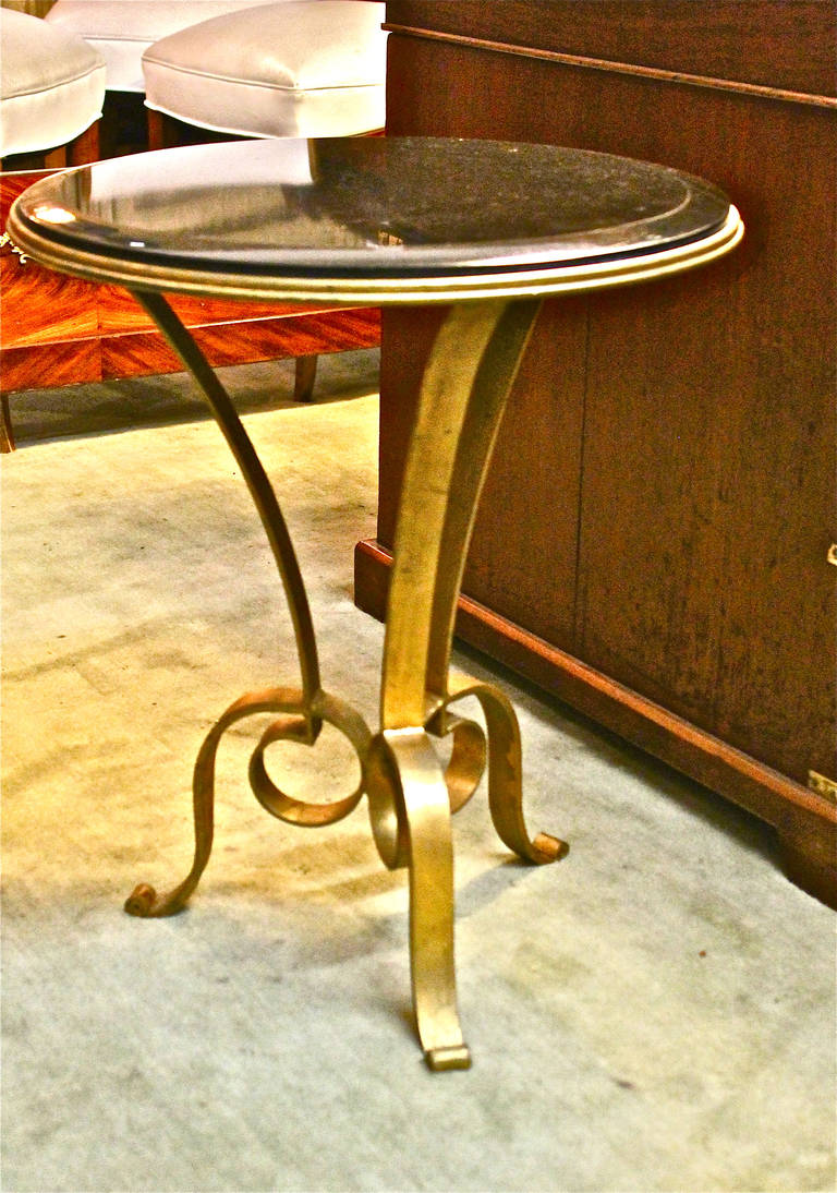 Pair of super chic French forged iron occasional tables in the style of Gilbert Poillerat. These tables were inspired by Poillerat, but most probably created iin the late 1970s or 1980s. The beautiful highly polished black granite tops are detailed