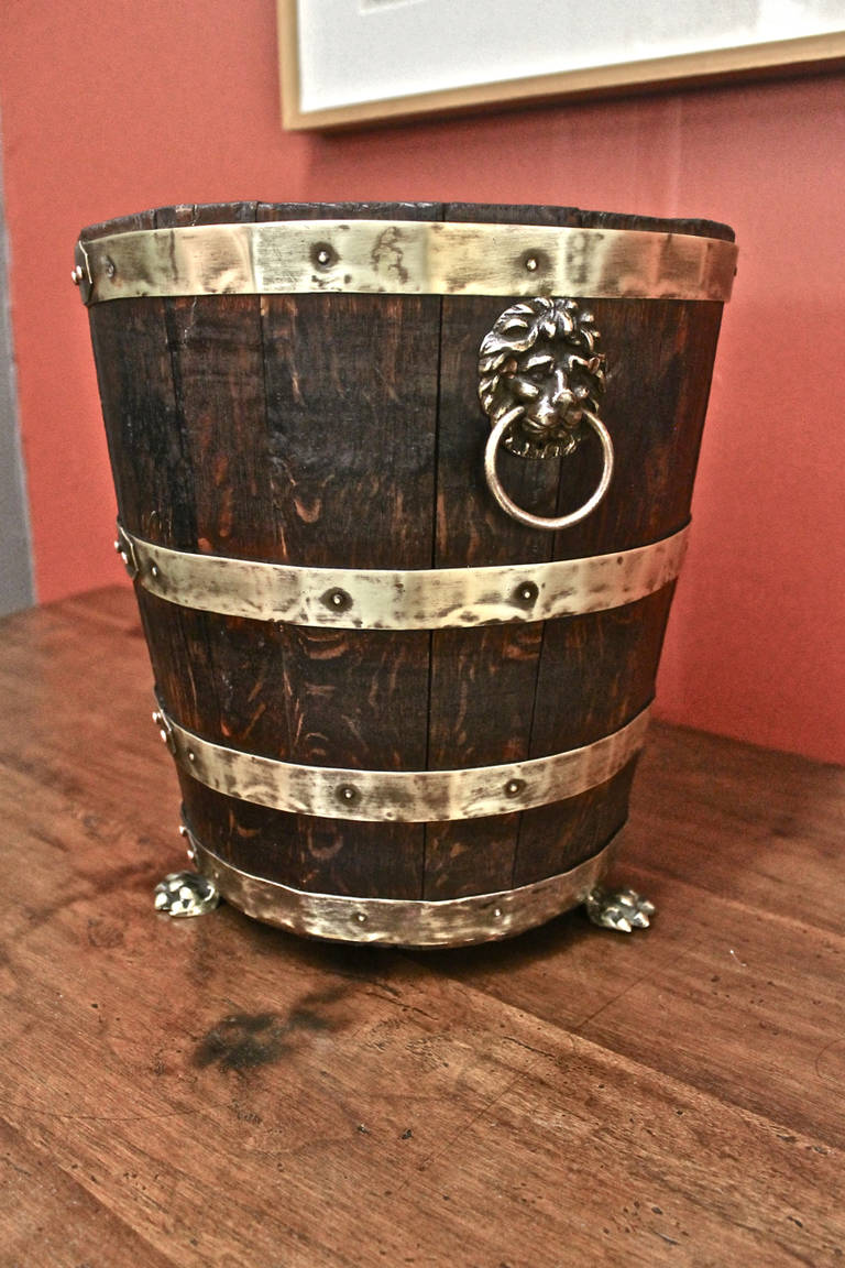 Highly desirable and hard to find English Regency oak and brass wine bucket that dates to circa 1810-1820. The quality of the brass lion's head and lion's paw hardware on this bucket is exceptional; when combined with the staved oak and brass