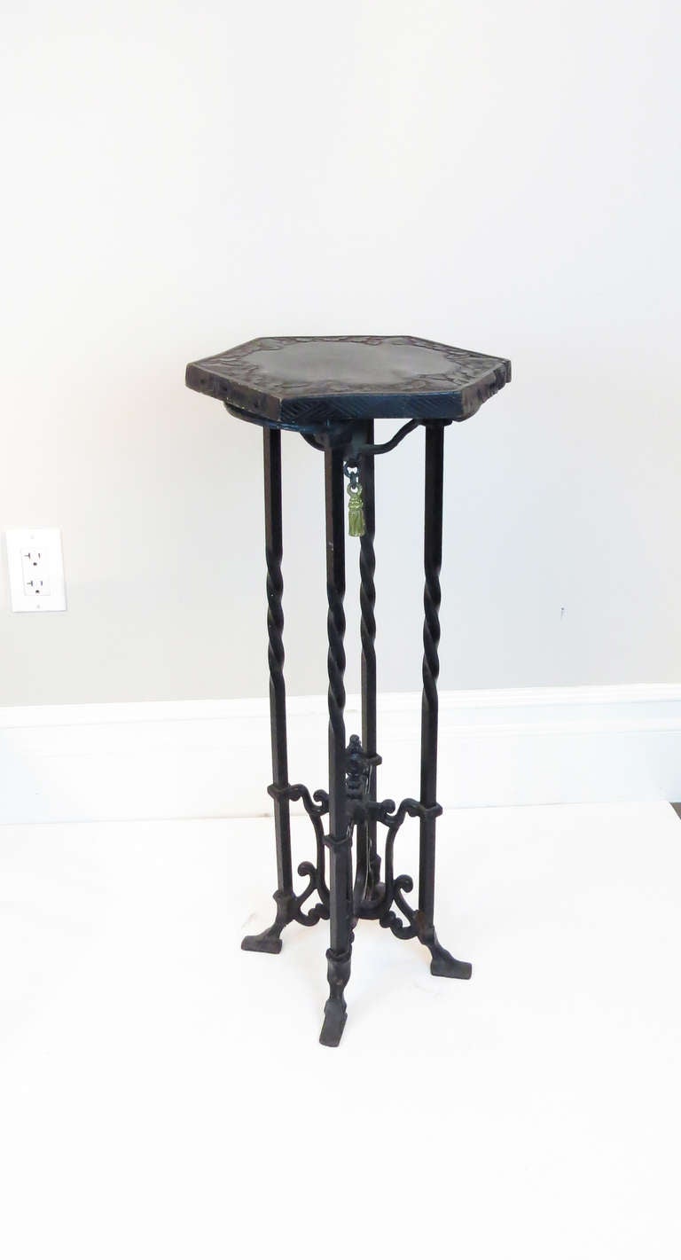 Unique pedestal with a wrought iron body and carved wood top. The piece has a hanging tassel under the top.