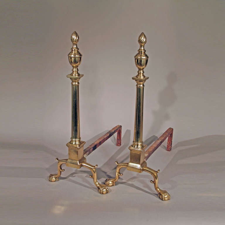 Probably Philadelphia, ca. 1775-1785.
Condition: Customary wear, minor imperfections, original iron dogs
Displaying exceptional form, this fully developed pair of embellished with swirl-flame finials above rounded columns and plinths supported by