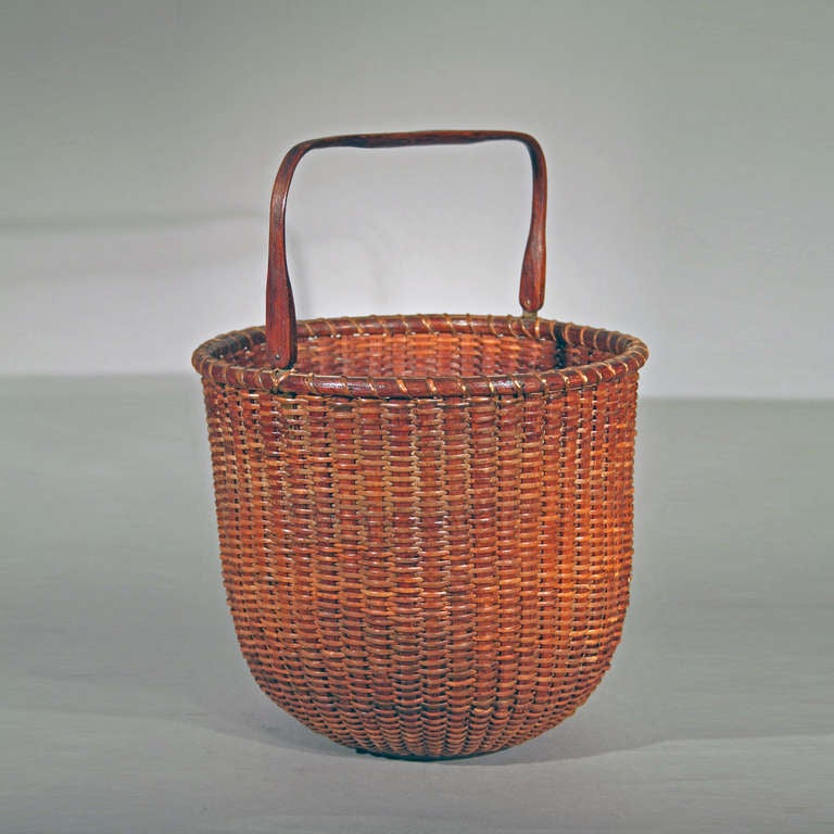 Probably Attributed to William D. Appleton
Nantucket, Massachusetts, early 20th c.
Hickory or ash, ratan, mahogany bottom
This rare tall or imposing size Nantucket Lightship Basket with a carved handle relates to other signed or known baskets by