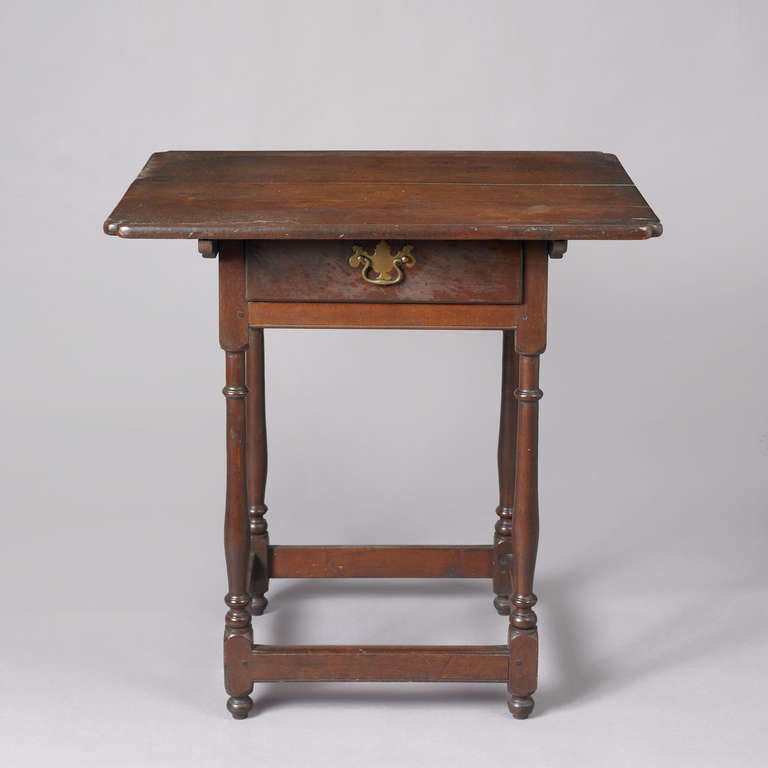 Pennsylvania, Probably Philadelphia, ca. 1750.
Walnut; secondary wood: poplar (drawer bottom)
This diminutive one drawer tavern table has a wonderful over hanging top with notched corners. The top is fitted with cleats underneath and is attached