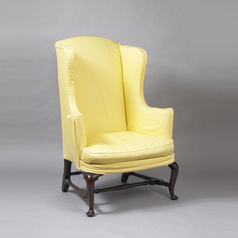 Massachusetts, probably Boston.
circa 1750.
This rare and classic form exhibits all the features of wing chairs made in the Boston area.  The shaped crest and wings of the chair are complimented by the scrolled arm rest which are supported by a