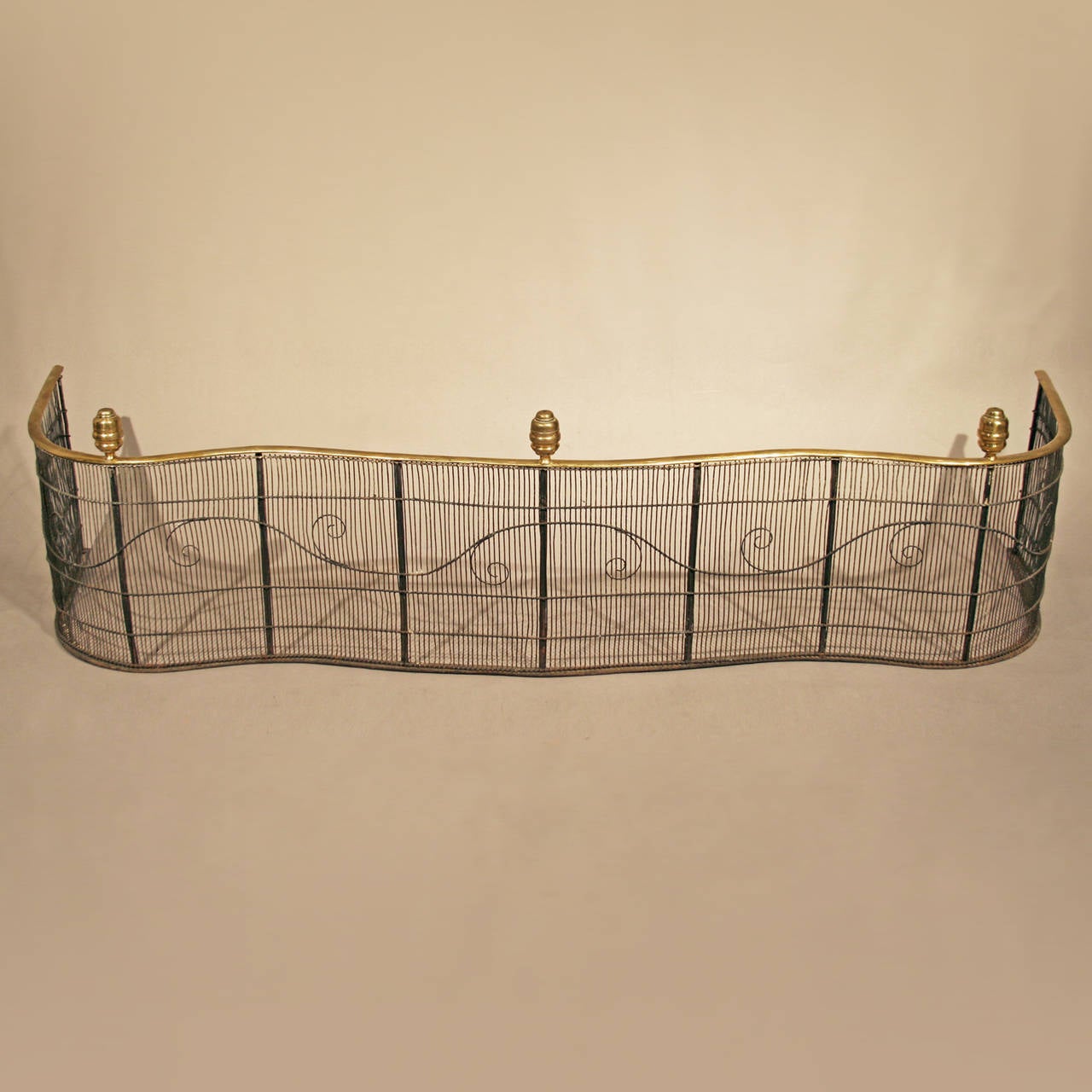 Rare Federal serpentine-front wire-work fender
American, probably Boston, circa 1800-1815.
Brass, square posts, forged iron wire-work.

Early developed Federal period, serpentine-front fenders with turned brass finials are very scarce to find.