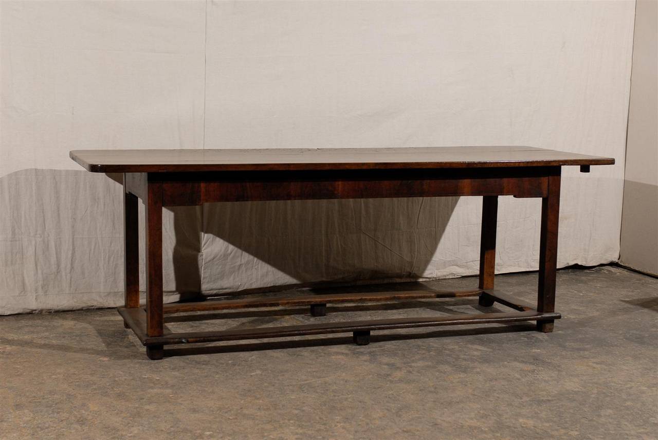 This Italian 19th century library table, made of walnut wood, will strike you by the sheer simplicity and beauty of its lines. The rectangular top sits on a linear apron and is raised on straight legs. The four legs are surrounded by four side