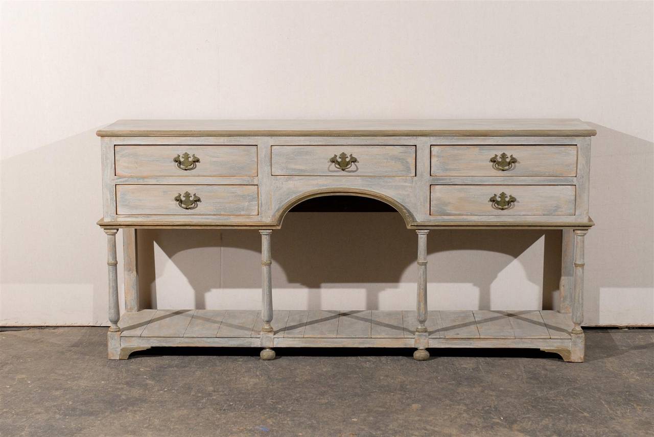 This English early to mid-20th century two-tiered painted pine sideboard is made of five drawers, spread around the charming arched skirt. 

It stands on bun feet in the center and bracket feet on its side. The turned legs in the front part of the