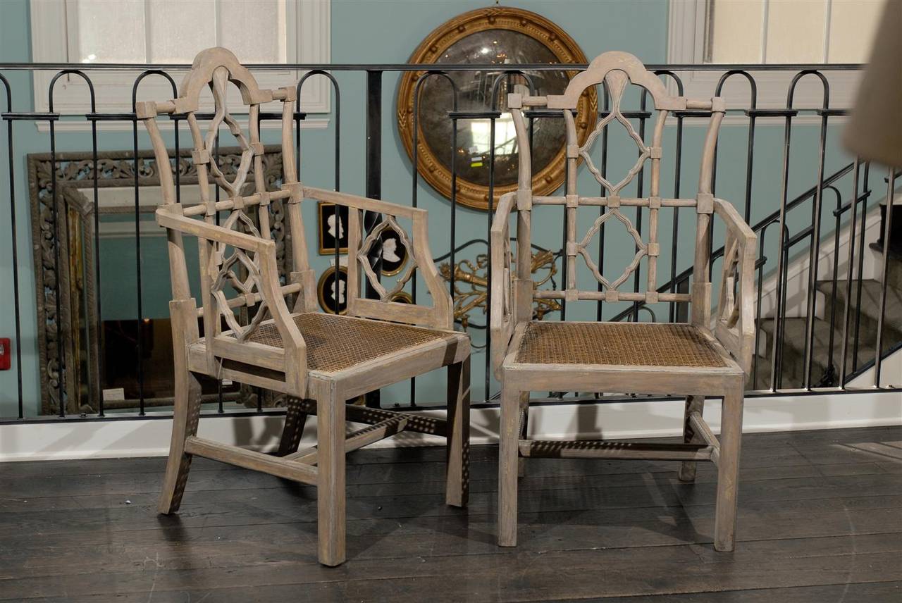 This is a pair of very elegant vintage Chinese Chippendale style wood armchairs. The backs with their typical Chinese Chippendale vocabulary and patterns, are slightly slanted. 

They have cane seats, a cross stretcher and rest on two back sabre