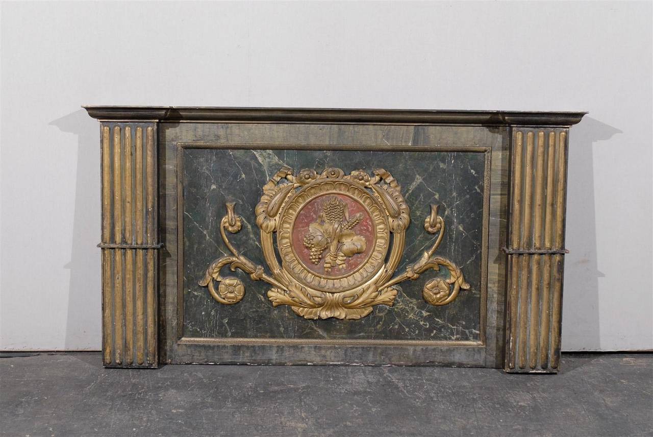 An early 19th century Italian decorative wall panel with flat fluted side columns or pilasters made of wood and gilt with original paint. 

The floral themed cartouche marking the center of the marbleized background shelters a lovely bouquet of