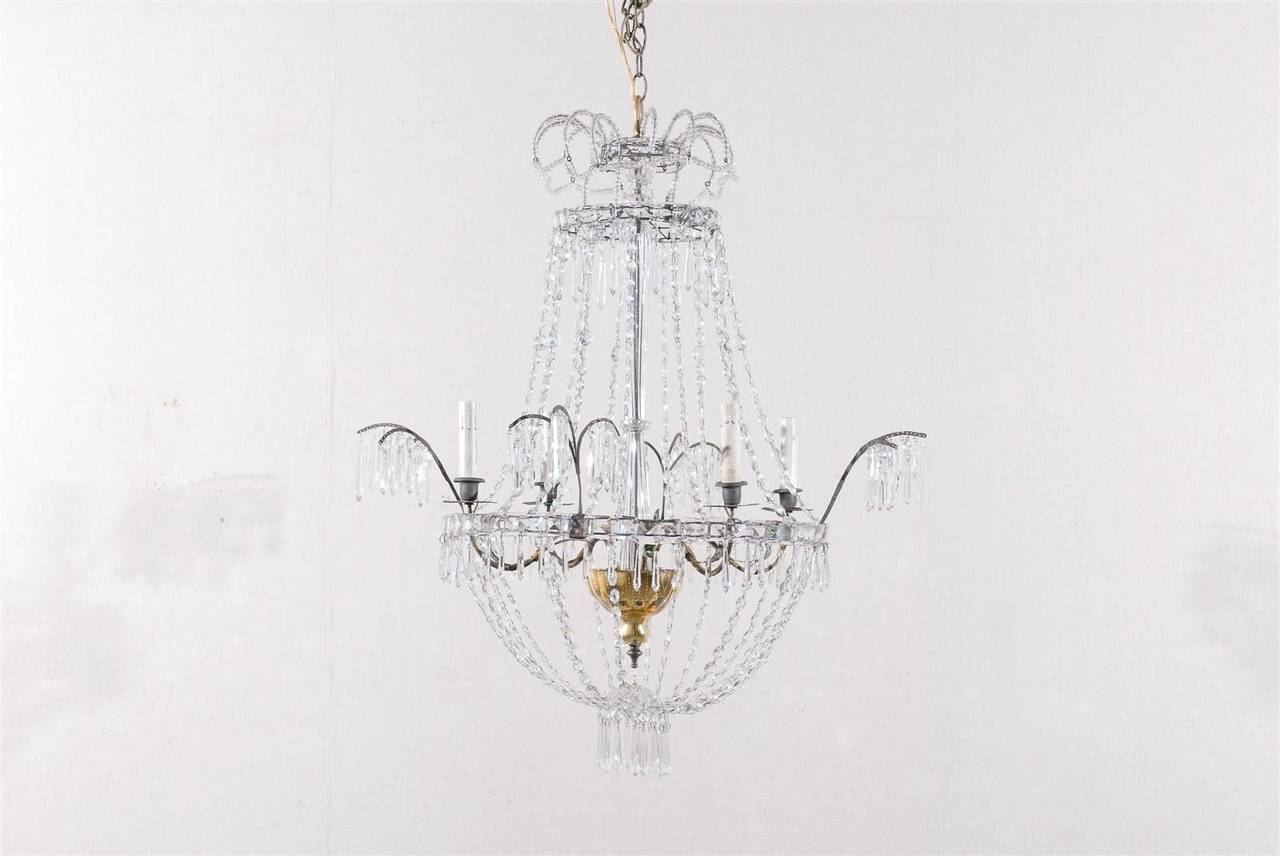 This early 20th century Italian four-light chandelier is made of a crystal central column with accents of gold mercury glass.

It all starts at the crown from which spring beaded arms, below which a ring of square crystals support the spear-shaped