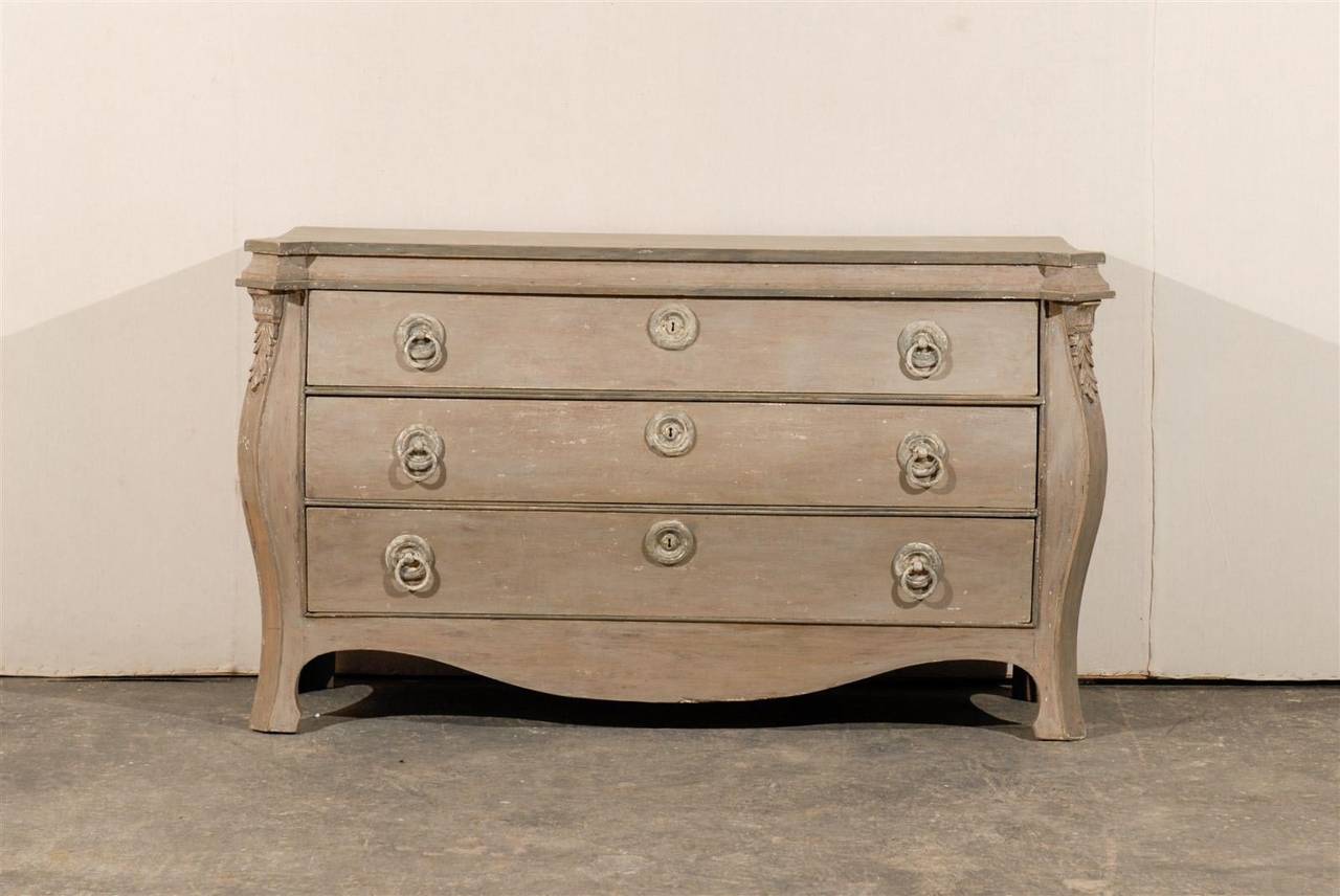 A 19th century European three-drawer painted wood chest with angled side posts, carved with acanthus leaf details. Nicely curved skirt and ring pulls on each drawer.