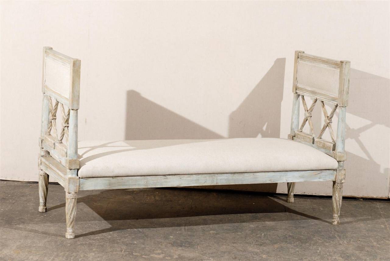 A 19th century Gustavian style upholstered painted wood daybed or bench with X-shaped slats and twisted legs.