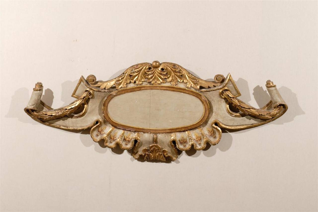 An exquisite 18th century Italian gilded and painted wooden wall plaque. This Italian large size wall decoration features a central cartouche, surrounded by a variety of motifs: reminiscent of the Baroque period, volutes and scrolls flank the sides