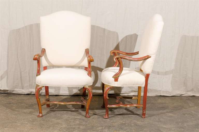 A pair of Italian fauteuils from the late 19th century. This pair of Italian wooden armchairs have their original red and gold tone color. These upholstered chairs from circa 1880 feature a nice slightly slanted camelback, cabriole legs in the front