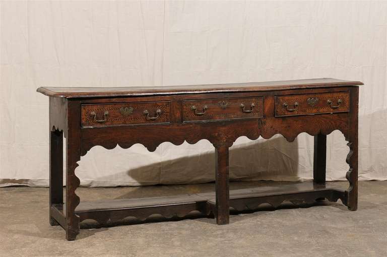 An 18th century three drawer sideboard made of walnut with delicate marquetry details around the drawers.