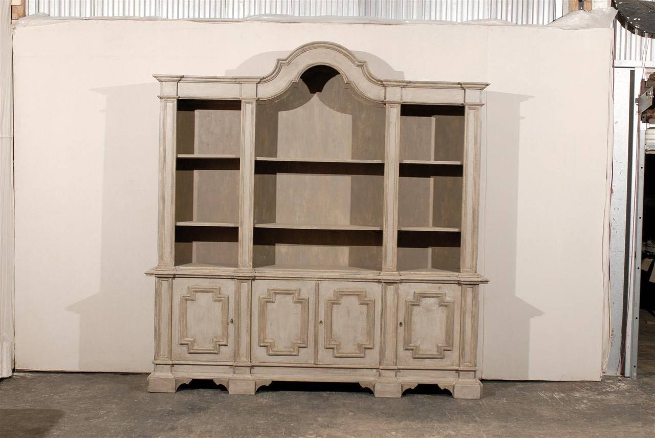 An Italian painted wood cabinet with bonnet top and sectioned open shelves over four carved doors with geometrical motifs, mid-20th century.
