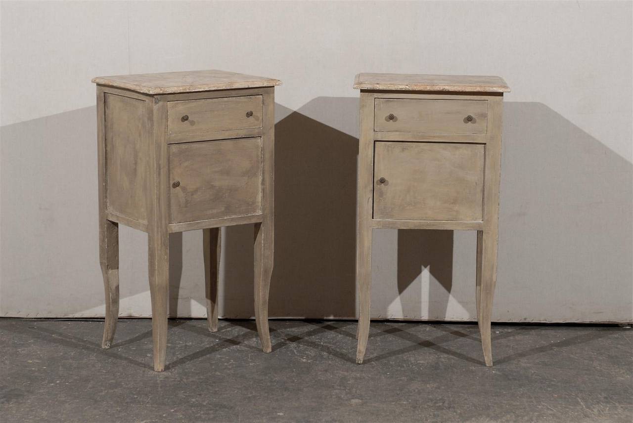 A pair of Italian nightstand tables or chests with single door and drawer and original marbleized tops, from the mid-20th century.