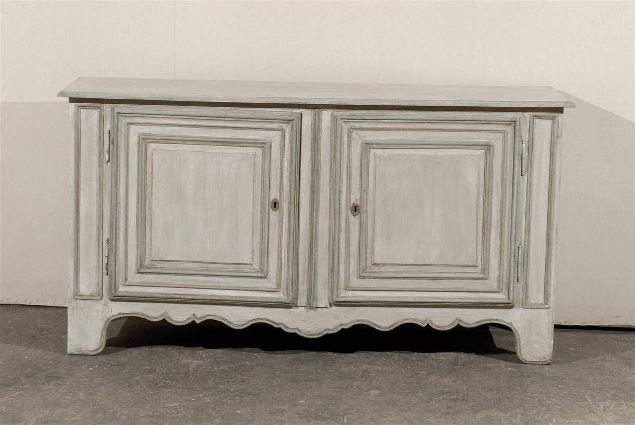 A French 19th century painted wood two-door buffet with scalloped skirt and inner shelf. The doors of this French buffet feature raised panels with carved molding. The doors do not lock but the key conveniently helps pull them opened. The general