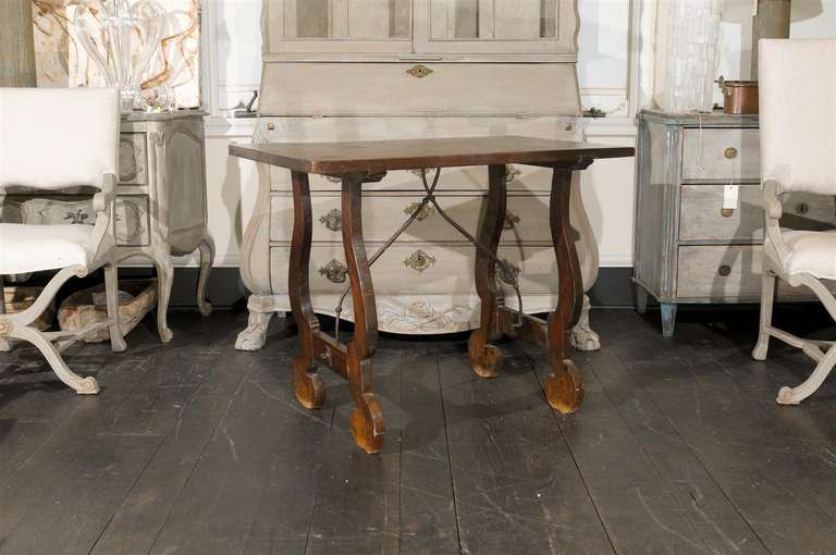 An Italian Fratino walnut table from the early 19th century. This Italian walnut side table features lyre shaped legs with hand-forged iron stretcher. Nice patina on this walnut side table which could conveniently decorate your office, entry, living