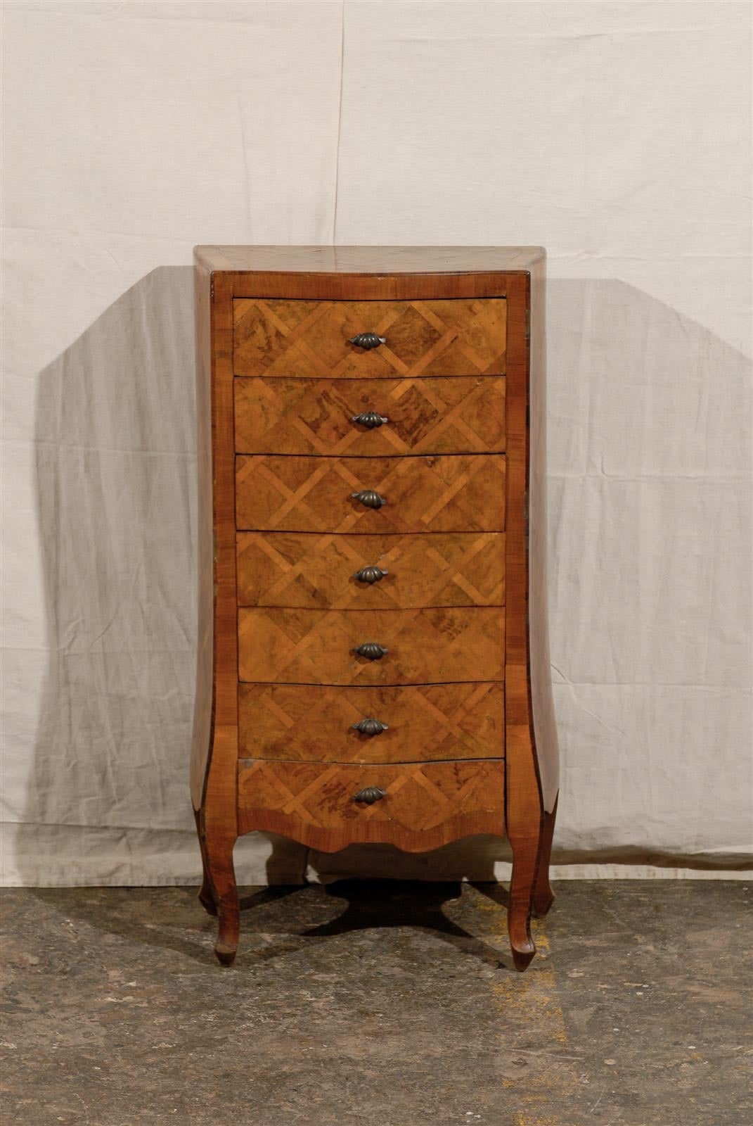 A lovely Italian olive wood marquetry semainier (seven-drawer tall chest) with canted sides, mid-20th century.