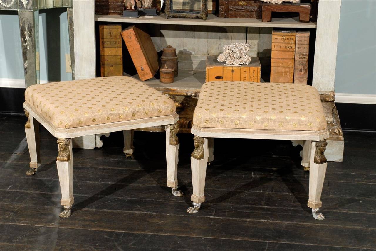 A pair of American Neoclassical style stools, circa 1950. This pair of vintage square shaped painted wood upholstered stools feature feminine 