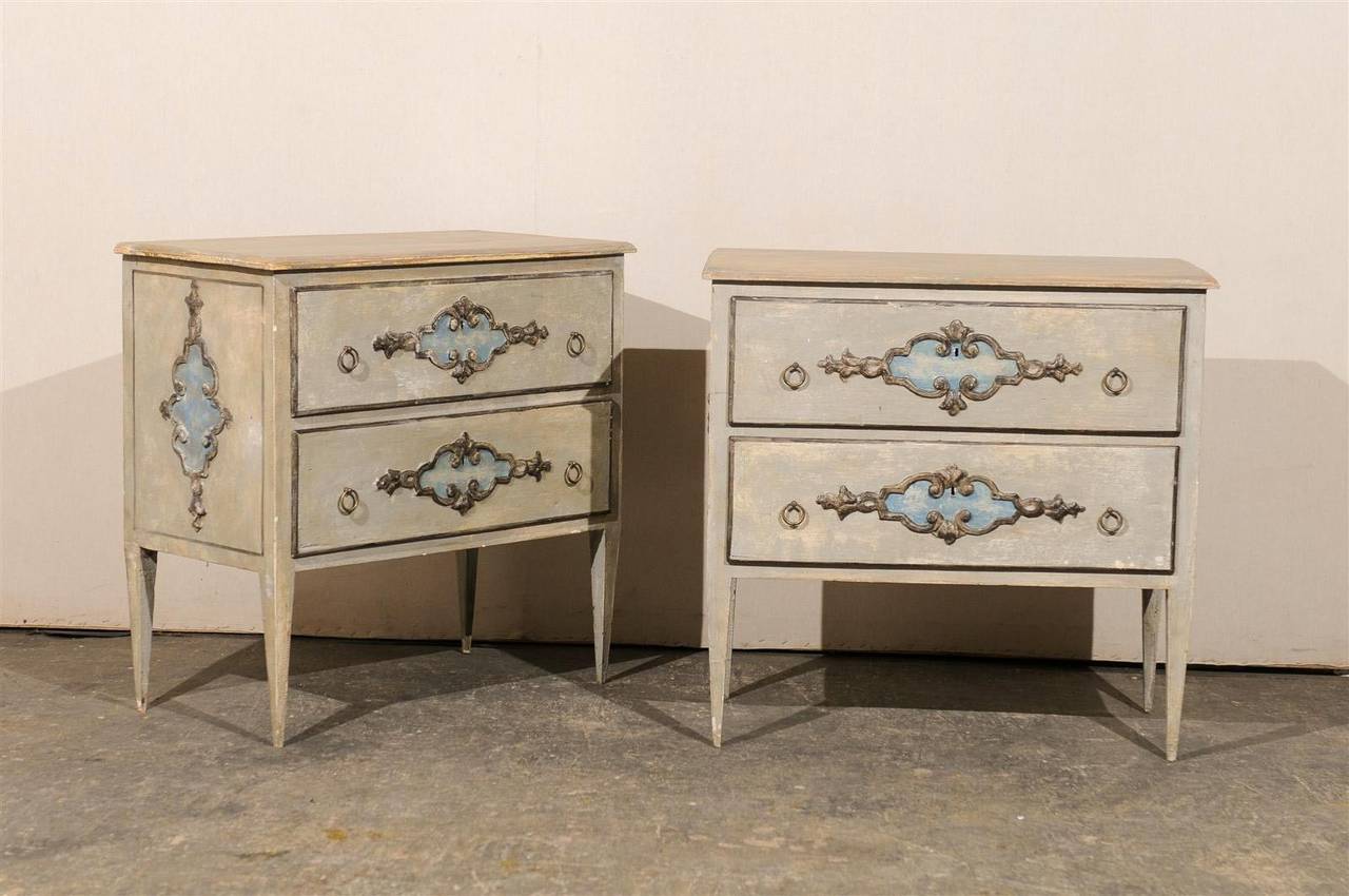 A pair of Italian painted wood small size two-drawer chests with lovely cartouche-like carvings and painted accents, on long tapered feet, 20th century.