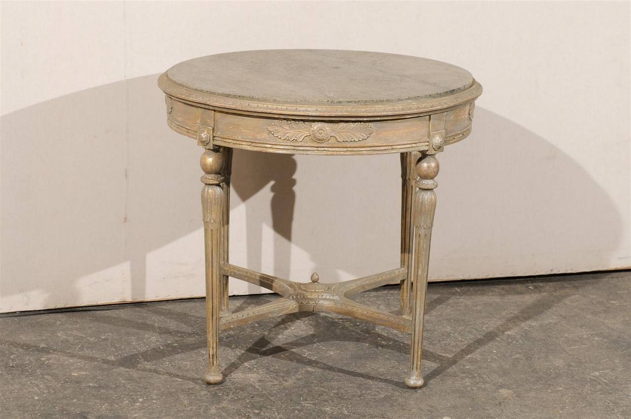 A lovely mid-19th century Swedish marble-top round center table made of painted wood with carved apron, elegant fluted legs and carved cross stretcher, circa 1850.