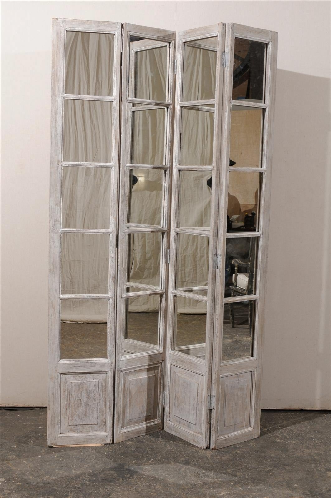 A pair of mirrored painted wood American screens from the mid-20th century with carved lower panels.

The measurements mentioned below are for each mirrored screen.